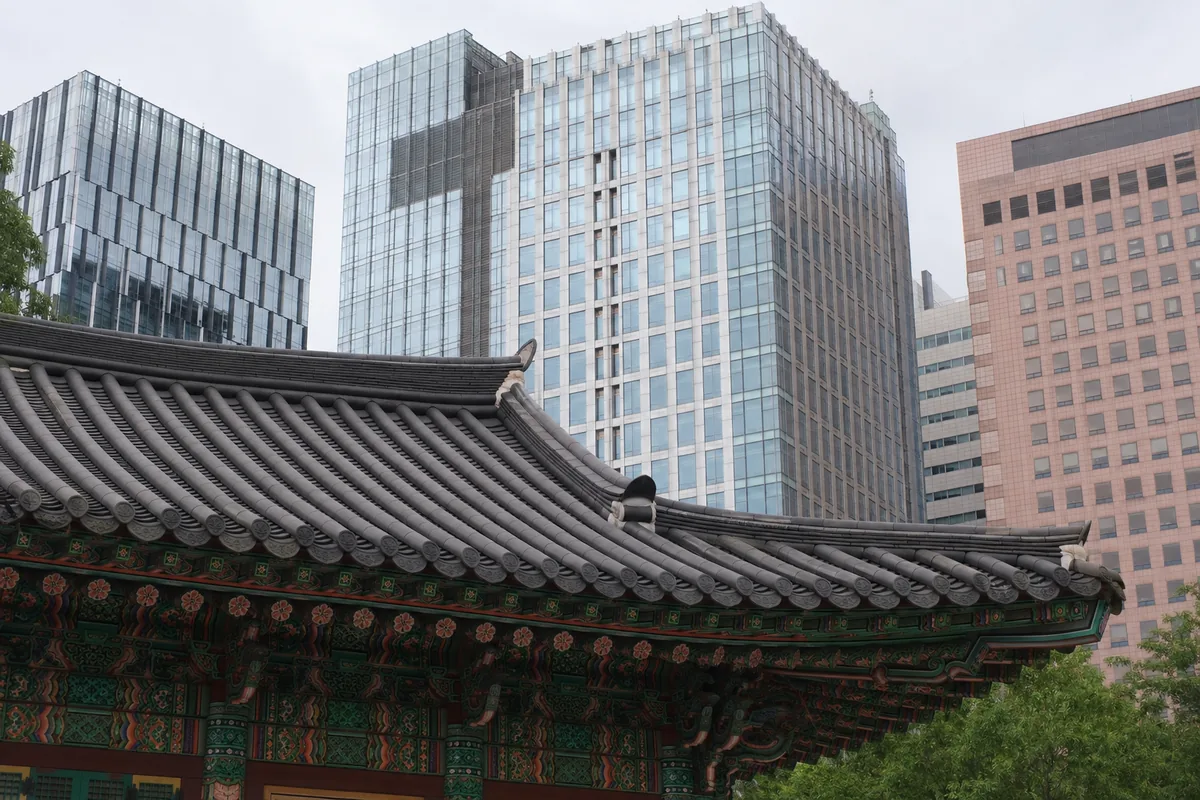 한낮 도심 고층빌딩 사이로 보이는 도심형 재물운 사찰의 기와지붕